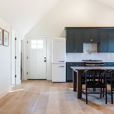 Kitchen with a retro-style fridge, vault ceiling, dark dining set, white tile backsplash, and dark gray cabinets